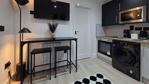 Una cocina moderna con televisión de pantalla plana, lavadora y cafetera.