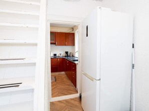 A kitchen with wooden cabinets, a white refrigerator, and a herringbone-patterned floor. - 10 Person Holiday Home in Bovlingbjerg (Bøvlingbjerg)