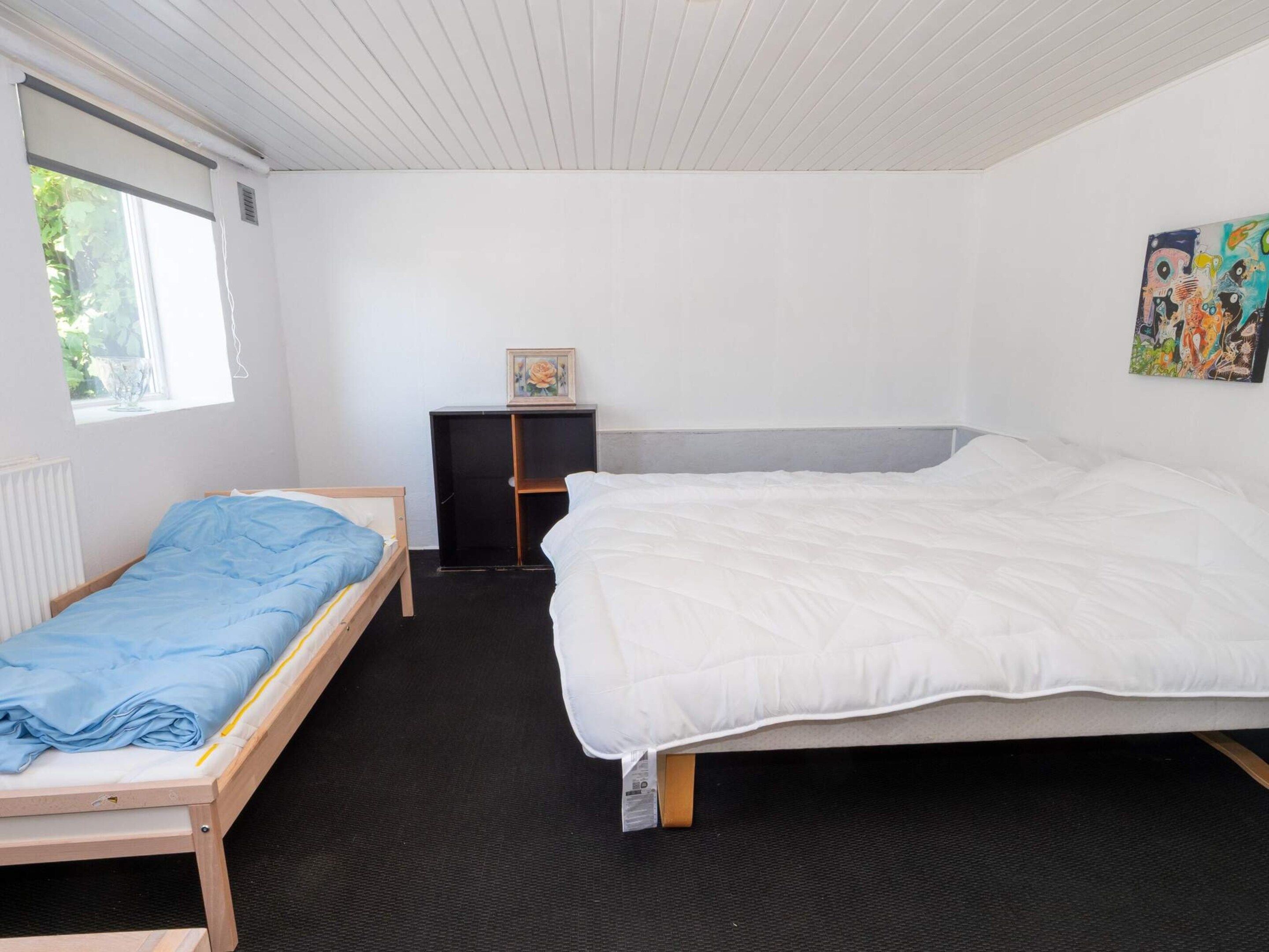 A room with two beds, a radiator, a window, and a painting on the wall.