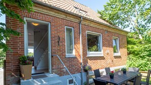 A brick house with a covered patio, a table with chairs, and a set of stairs leading to the entrance. - 10 Person Holiday Home in Bovlingbjerg (Bøvlingbjerg)