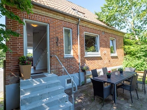 A brick house with a covered patio, a table with chairs, and a set of stairs leading to the entrance. - 10 Person Holiday Home in Bovlingbjerg (Bøvlingbjerg)