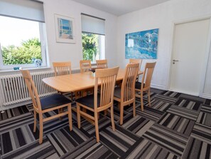 A dining room with a rectangular table and six chairs, large windows with blinds, a radiator, and a door. - 10 Person Holiday Home in Bovlingbjerg (Bøvlingbjerg)