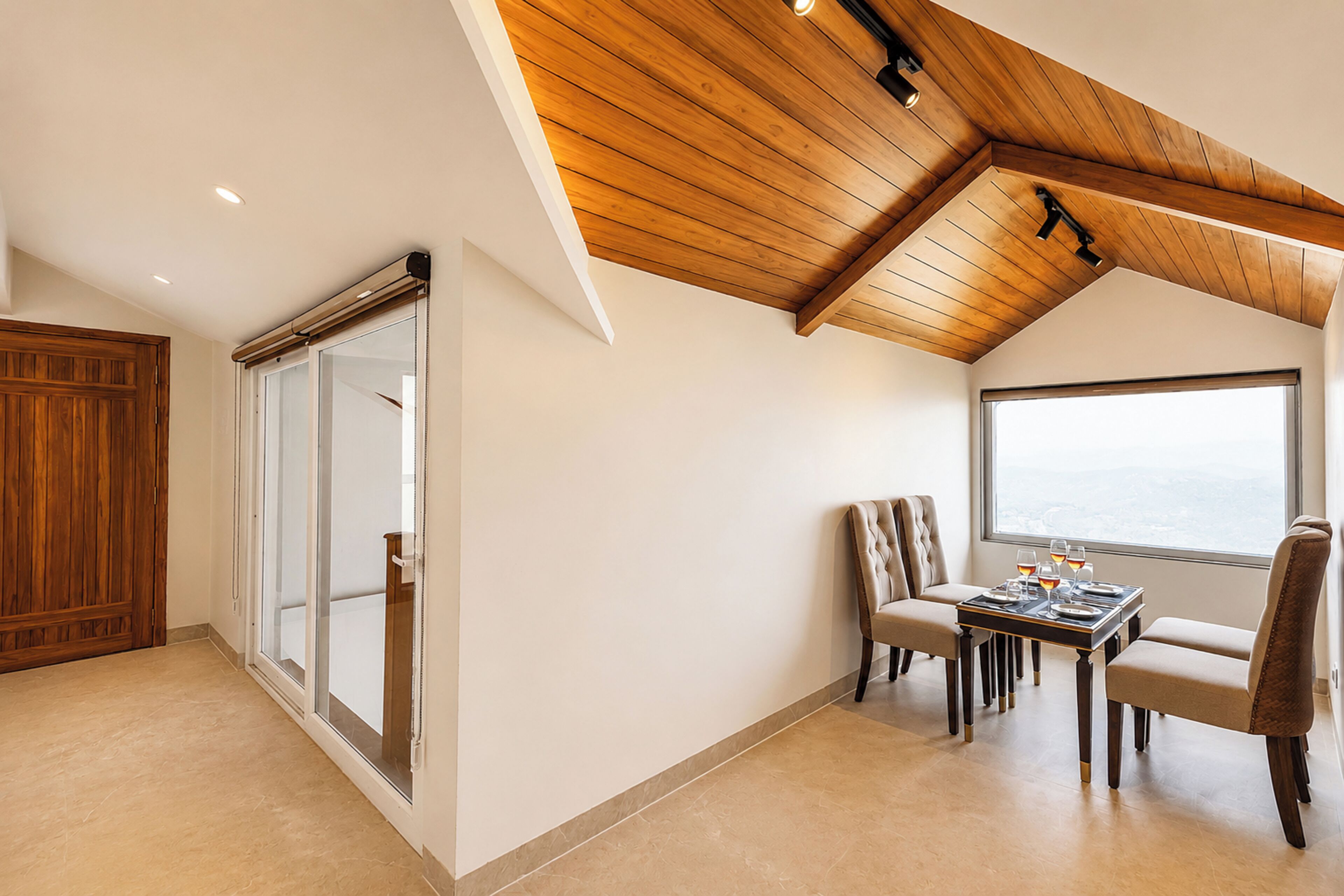 A dining area with a table set for four, a large window, and a wooden ceiling.