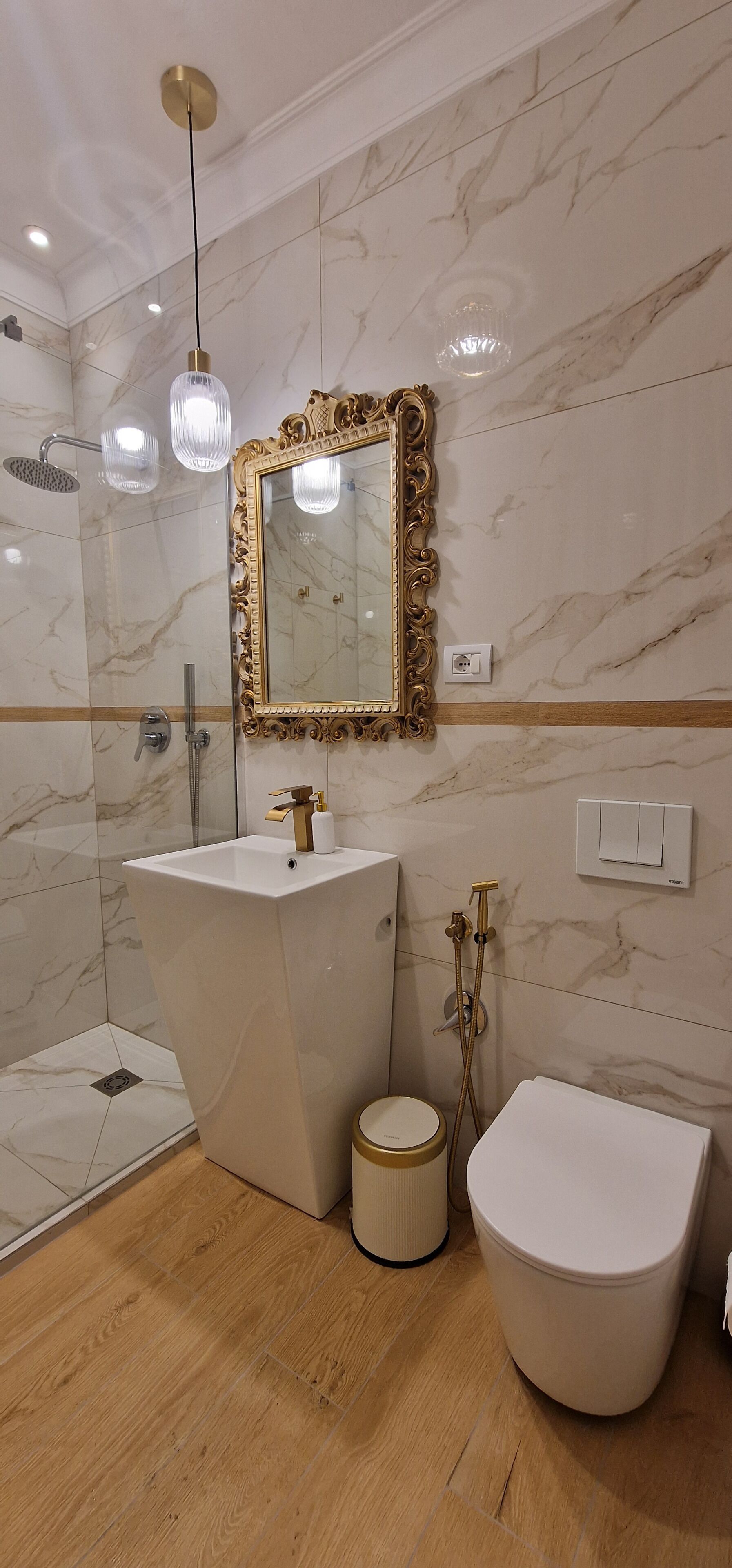 A bathroom with a marble wall, a freestanding bathtub, a toilet, and a shower area.