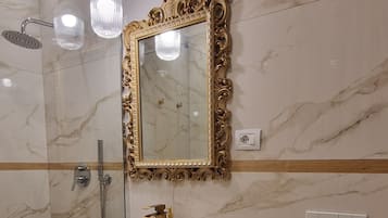 Une salle de bain avec un mur en marbre, une baignoire sur pieds, des toilettes et un espace douche.