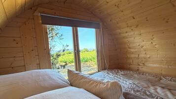 Una habitación acogedora de madera con dos camas, una ventana y vistas a la vegetación.