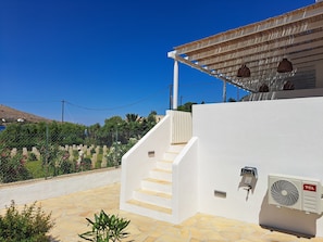 A white building with a stone staircase leading to a covered area with a fan and a TCL logo. - ALINTHEA 1, Alinda, Leros (Leros)