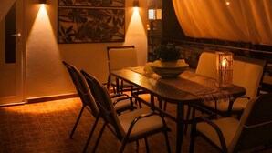 A dining area with a round table, chairs, a plant, and wall-mounted lighting. - Holiday Home 'Domenica Apartment' with Mountain View, Wi-Fi and Air Conditioning (Salamina)
