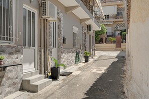 A narrow street with buildings featuring stone facades, metal railings, and potted plants. - Holiday Home 'Domenica Apartment' with Mountain View, Wi-Fi and Air Conditioning (Salamina)