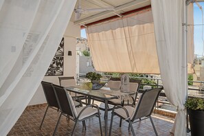 Ein Balkon mit Tisch und Stühlen, einem Blumentopf und Blick auf die Stadtlandschaft.