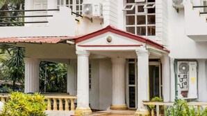 A building with a covered entrance, columns, and a small fountain. - Deluxe With Balcony Calangute Goa (Calangute)