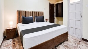 A bedroom with a bed, nightstand, lamp, and a door. - Deluxe With Balcony Calangute Goa (Calangute)