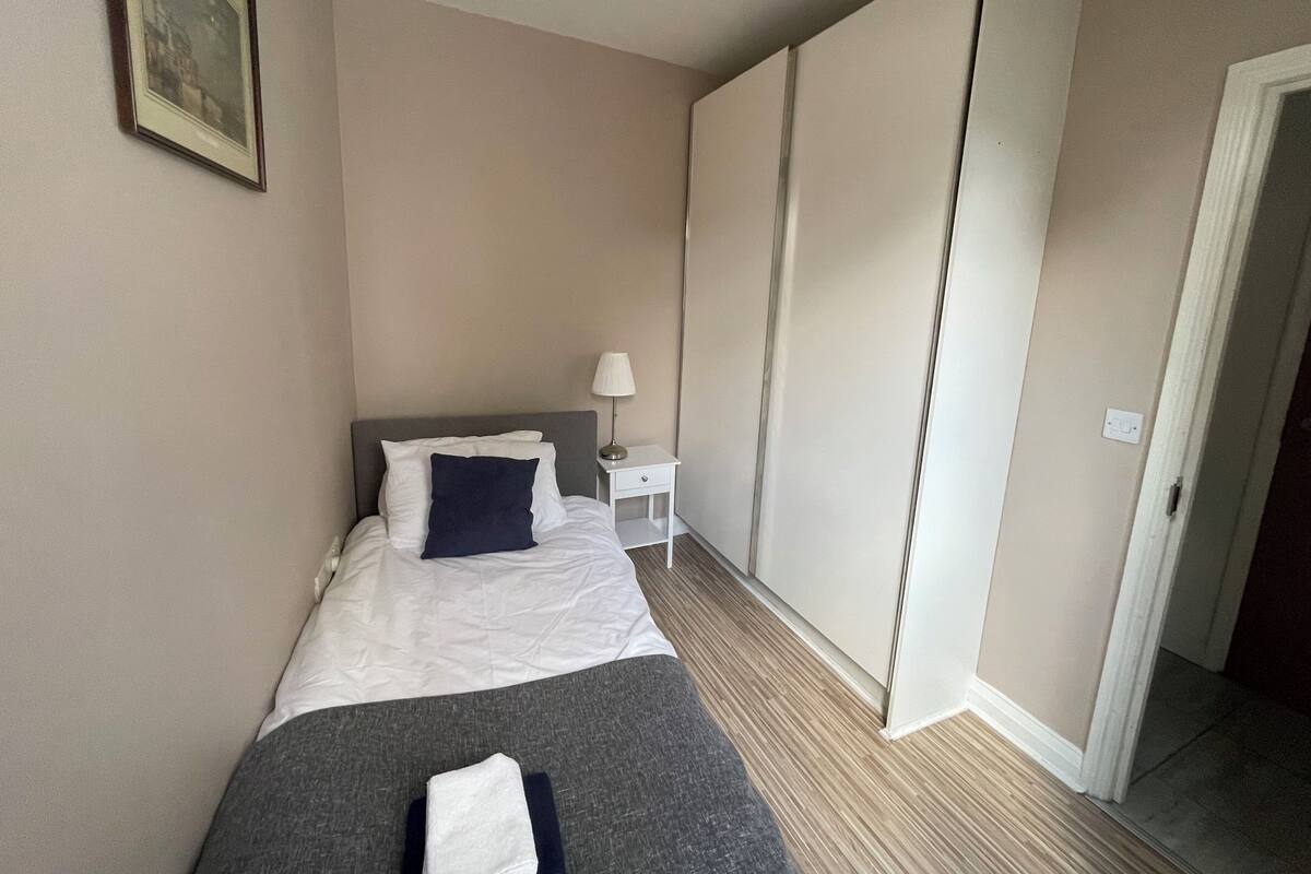 Una habitación de hotel con cama, mesita de noche, lámpara y armario.
