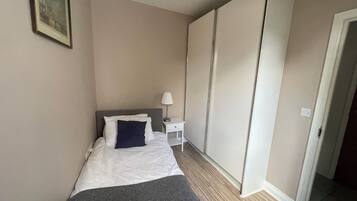 A hotel room with a bed, a nightstand, a lamp, and a wardrobe.