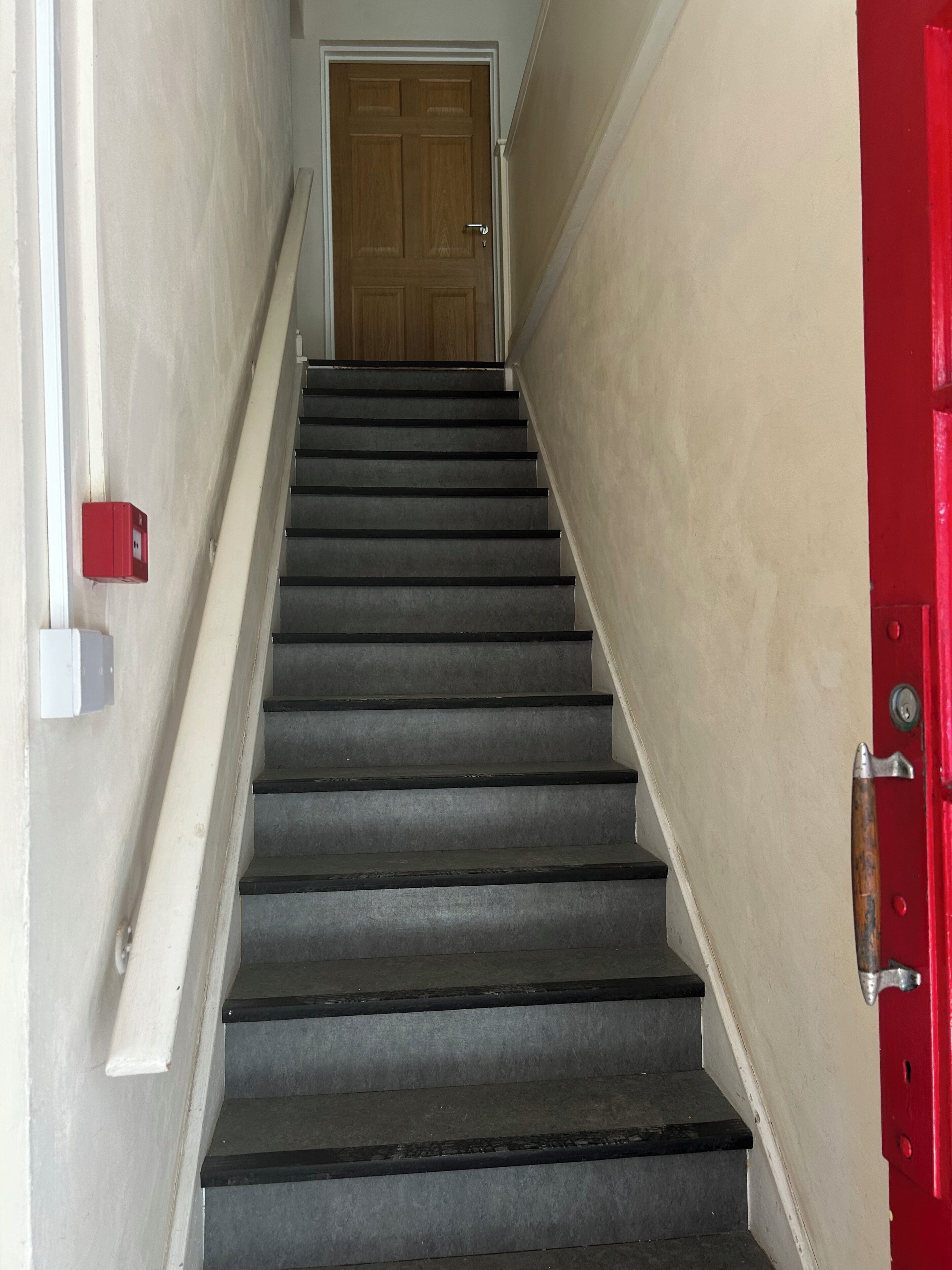 Una escalera que lleva a una puerta con picaporte rojo.
