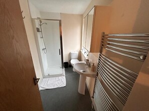 A bathroom with a shower, toilet, sink, and a towel rack. - The Nook Bedford (Bedford)