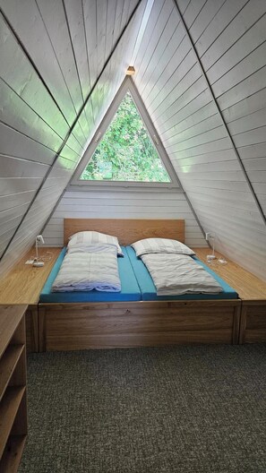 A small, triangular attic bedroom with a single bed, a window, and a desk. - Vacation Home 1 (Kinding - Kratzmühle)