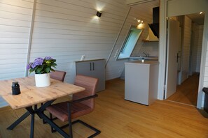 A compact kitchen with a wooden table, a chair, a potted plant, and a refrigerator. - Vacation Home 1 (Kinding - Kratzmühle)