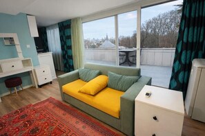 A room with a sofa, a small table, a desk, and a window with a view of buildings. - Turquoise İstanbul Hotel (İstanbul)