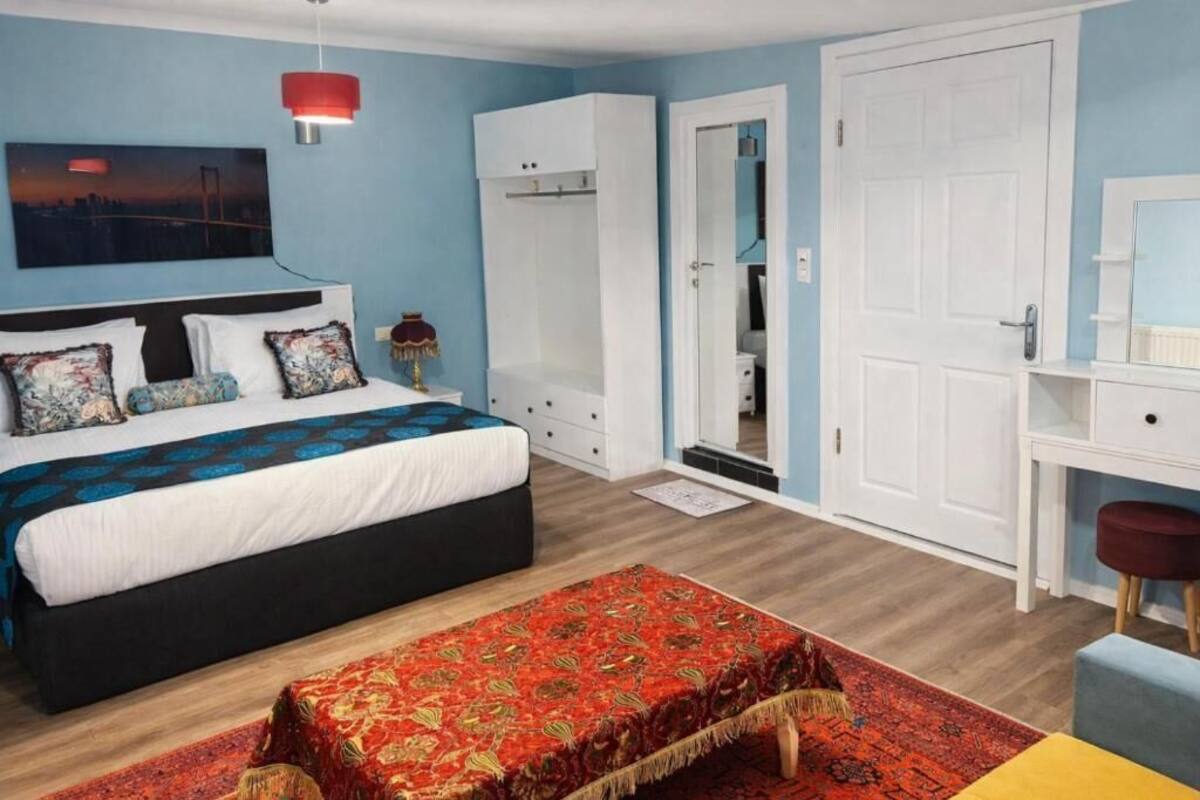 A bedroom with a bed, a desk, a wardrobe, and a mirror.