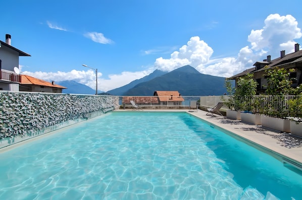A swimming pool with clear water, a mountain in the background, and a view of a house.
