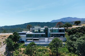 Una casa moderna de dos pisos con techo plano, ventanas amplias y vistas a una cadena montañosa.