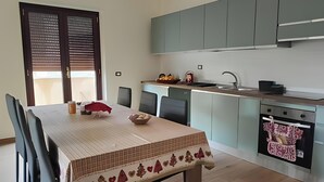 Eine moderne Küche mit Essbereich, ausgestattet mit einem Tisch, Stühlen, einer Spüle und einem Herd.