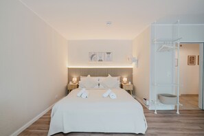 Un lit bien fait, avec des serviettes, une lampe de chevet, une étagère suspendue et une étagère fixée au mur.