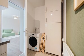 Ein Waschraum mit Waschmaschine, Wäscheständern aus Holz und einem Heizkörper.