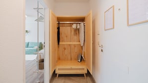 Ein begehbarer Kleiderschrank aus Holz mit Kleiderstange, Wäscheständer und einer Sitzbank.