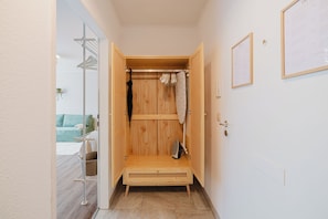 Ein begehbarer Kleiderschrank aus Holz mit Kleiderstange, Wäscheständer und einer Sitzbank.