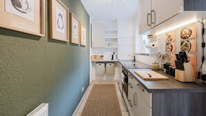 Eine moderne Küche mit weißen Schränken, einer Holz Arbeitsplatte und gerahmten Kunstwerken an der Wand.
