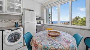 Una cucina con lavatrice, forno a microonde e vista mare.