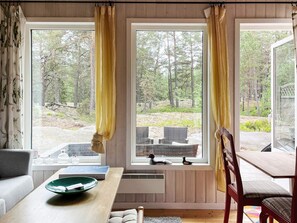 A room with large windows, a dining table, a sofa, and a chair. - 4 Star Holiday Home in Blido (Blidö)