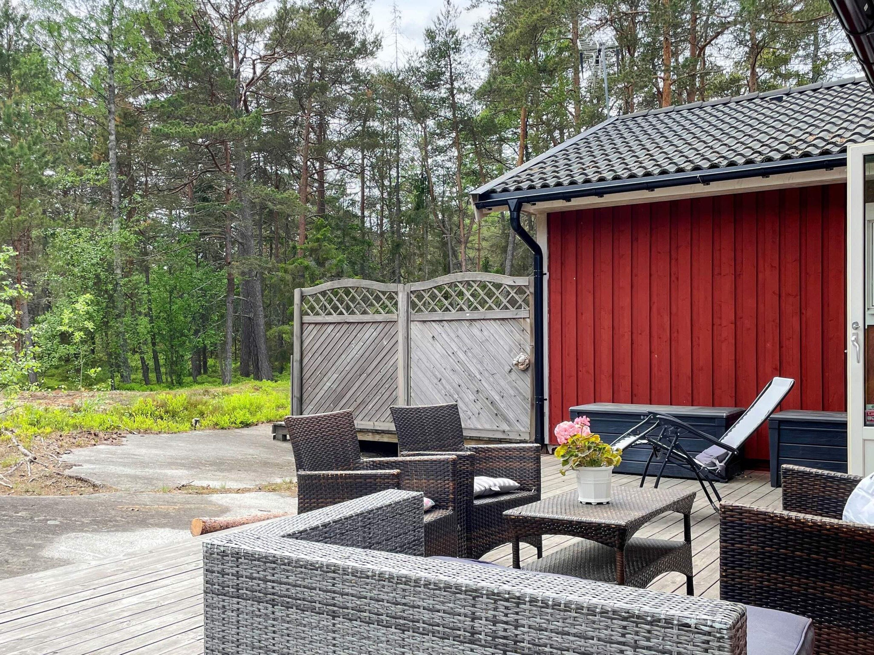 An outdoor patio with wicker furniture, a red building, and a wooden fence.