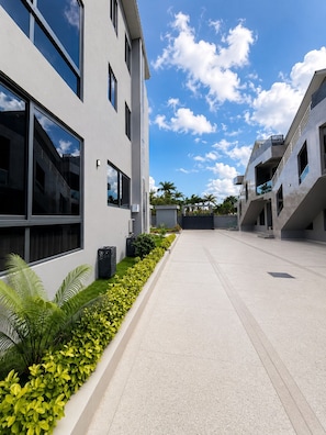 A modern building with large windows, a paved walkway, and a clear sky.