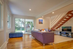 Un salón espacioso con un sofá grande, un televisor y una escalera.