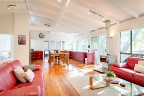 A spacious living area with a red sofa, a glass coffee table, and a dining area with wooden chairs. - Casa Lagoona - Coastal Retreat by the Beach (Quindalup)
