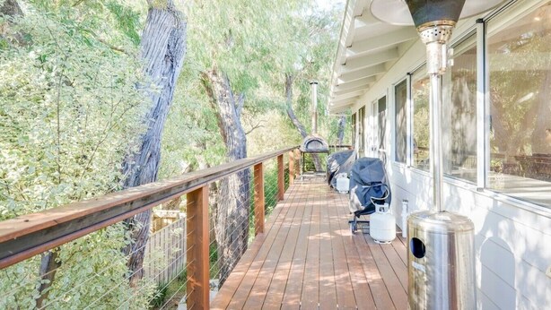 A wooden deck with a railing, a covered grill, and a trash can. - Casa Lagoona - Coastal Retreat by the Beach (Quindalup)