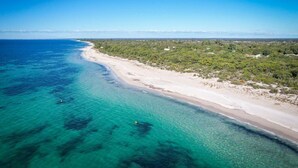 An aerial view of a beach with clear turquoise waters, a sandy shoreline, and dense greenery in the background. - Casa Lagoona - Coastal Retreat by the Beach (Quindalup)