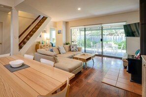 Ein modernes Wohnzimmer mit einem Holzesstisch, einer Couch und einer Treppe.