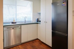 Eine Küche mit Geschirrspüler, Spüle, Kühlschrank und Schränken.