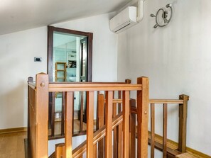 A wooden staircase with a glass door leading to a room. An air conditioning unit is mounted on the wall. - EnDi - Cozy & Authentic Apartment in Asti (Asti)