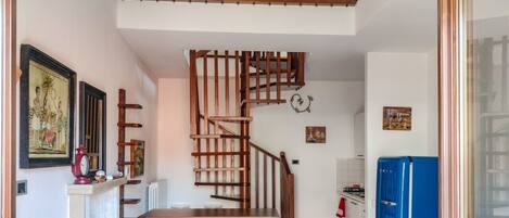 A kitchen with a wooden staircase, a dining table, and a blue refrigerator.