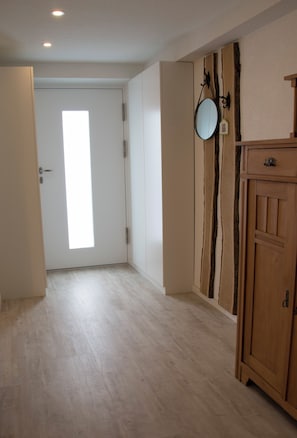 Ein Flur mit Holzboden, einer weißen Tür und einem Spiegel an der Wand.