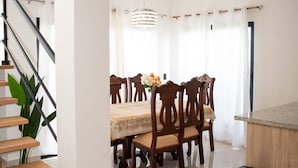 A dining area with a table, chairs, a chandelier, and a staircase.