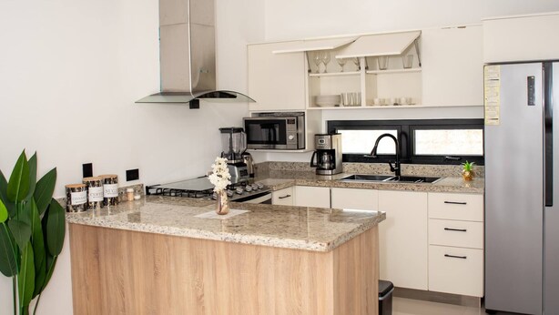 A modern kitchen with a central island, stainless steel appliances, and a minimalist design. - Luxurious Punta Cana House 3 Bedrooms, Shared Pool, BBQ (Punta Cana)