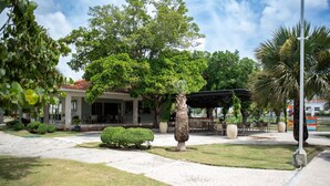 A courtyard with a building, a palm tree, and a covered seating area. - Luxurious Punta Cana House 3 Bedrooms, Shared Pool, BBQ (Punta Cana)