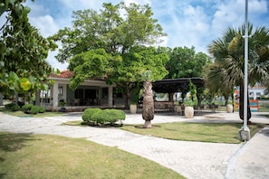 A courtyard with a building, a palm tree, and a covered seating area.