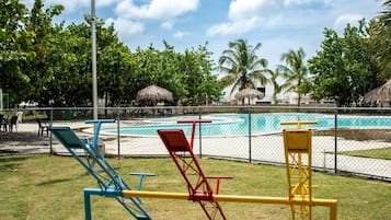 Un terrain de jeux équipé d’installations d’exercice, une piscine et des palmiers.